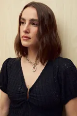 Top blanco con textura tramada, escote en V con leve frunce central, mangas cortas con elástico y volado sutil en el ruedo. Tejido con elasticidad.