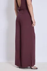 Pantalón ancho de tiro alto color vino, con pliegues frontales y bolsillos laterales.