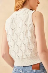 Chaleco de punto color crudo con diseño calado de corazones, sin mangas y con botones joya.