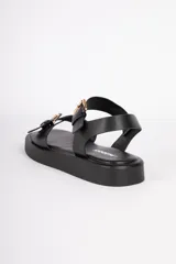 Sandalias negras de cuero sintético con agarre en tobillo y empeine, ambos con hebillas metálicas ajustables color dorado. Cuentan con una plataforma de 3cm.