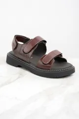 Sandalias marrones de cuero con suela de goma negra y ajuste con velcro.