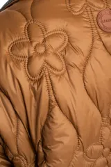 Campera capitoneada de color marrón con diseño de flores pespunteadas, cuello camisero en contraste oscuro y cierre frontal de cremallera.