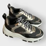 Zapatillas deportivas color beige con cordones a rayas en blanco y negro, suela de goma con plataforma y diseño chunky.
