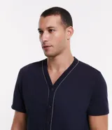 Conjunto de pijama corto azul marino con camisa de manga corta abotonada y short con cintura elástica. Presenta detalle de ribete contrastante en color blanco en el cuello, el frente de la camisa y el ruedo de las mangas.