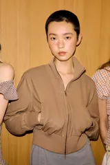 Chaqueta bomber de corte cropped confeccionada en material efecto piel color beige, con cuello subido, puños y cintura en rib elástico a tono, cierre frontal con cremallera y bolsillos laterales de vivo.