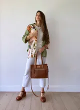 Cartera bandolera de cuero color tostado, con correa larga regulable, bolsillo frontal y forro de tela.