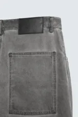 Pantalón de jean gris de corte amplio, estilo balloon fit, con cinco bolsillos, cierre frontal con cremallera y botón, y efecto de color lavado en toda la prenda.