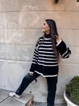 Sweater negro con rayas horizontales blancas, de cuello alto y corte holgado.