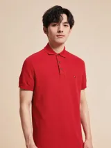 Chomba Tommy Hilfiger color rojo de corte slim, con cuello polo, cartera de dos botones, mangas cortas con ribete blanco y logo de la marca bordado en el pecho.