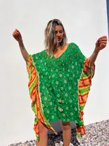 Túnica corta verde con estampado de flores blancas y detalles bordados en el escote. Mangas anchas con terminación en tela estampada a rayas naranjas y blancas.