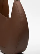 Bolso hobo grande color marrón con textura granulada. Tiene un compartimento con cierre magnético, un bolsillo interior y asa corta regulable.