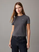 Remera gris de algodón con cuello redondo, mangas cortas y corte crop. Logo de Calvin Klein bordado en el pecho y estampado en la espalda.