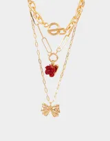 Set de tres collares dorados con diferentes cadenas de eslabones y dijes metálicos: cadena gruesa con cierre de barra, cadena con eslabones rectangulares y dije de rosa roja, y cadena con dije de moño.