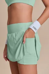 Pollera deportiva color verde lima, con short interno y bolsillo en la cintura.