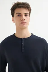 Sweater de punto azul marino, de corte recto y manga larga, con cuello redondo y tapeta con botones.