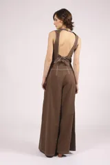 Pantalón negro de tiro alto, corte ancho y largo, con pliegues frontales y pespuntes contrastantes en blanco en la cintura y bolsillos.