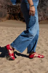 Sandalias rojas de cuero con tiras entretejidas, punta almendrada, correa con hebilla al tobillo y taco cuadrado bajo.