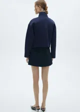 Chaqueta bomber azul marino con diseño crop, cuello alto, cierre delantero con cremallera, dos bolsillos laterales, diseño recto, oversize y manga larga.