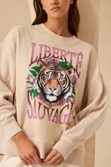 Buzo color beige de algodón con cuello redondo y mangas largas. Estampado frontal con un tigre, flores y la frase 'Liberté Sauvage'.