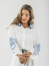 Camisa blanca de tela fresca con cuello camisero celeste y mangas abullonadas con apliques en denim celeste.