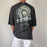 Remera gris con efecto gastado y estampado en la espalda con diseño abstracto en tonos verdes y blancos.