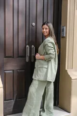 Blazer verde seco de lino, con corte entallado, solapas clásicas y cierre frontal con botones.