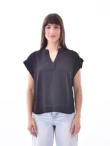Blusa negra de corte holgado, con cuello tipo polo y mangas cortas.