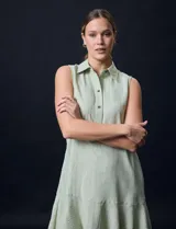 Vestido corto blanco de gasa, sin mangas, con cuello camisero, abertura central con botones y terminación de ruedo con volado.
