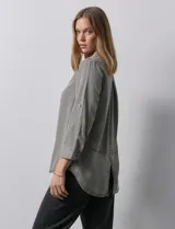 Camisa celeste de tencel con cuello con solapa, escote en V, abertura central con botones y mangas 3/4 regulables con presilla y botón.