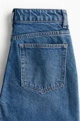 Pantalón de jean azul de corte recto, con tiro alto, cinco bolsillos y cierre con botones.
