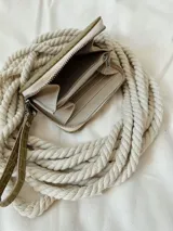 Billetera pequeña de cuero verde con textura tipo cocodrilo, forrada, con cierre metálico y pulsera para colgar de la muñeca.