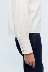 Camisa blanca con rayas verticales, de manga larga y cuello tipo mao, con botón frontal.