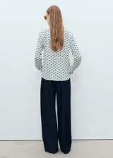 Camisa de manga larga con puños abotonados, cuello camisero y cierre frontal con botones ocultos. Presenta un estampado geométrico en tonos azul y verde sobre fondo blanco, y corte recto.