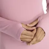 Camiseta deportiva de manga larga, color rosa claro, con cuello alto y cierre frontal parcial de un cuarto. Presenta orificios para los pulgares en los puños.