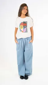 Remera blanca con estampado gráfico de rostros, de corte suelto y manga corta.