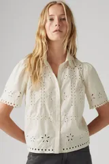 Camisa color crema con bordado calado, cuello clásico, manga corta abullonada y cierre frontal con botones.