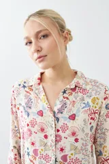 Camisa de manga larga con cuello clásico y estampado floral multicolor sobre fondo blanco.