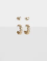 Set de dos pares de aros dorados: un par de aros pasantes con forma de corazón y un par de aros argolla con corazones.