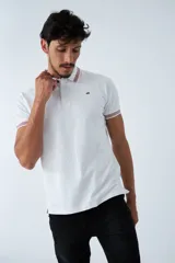 Remera cuello polo blanca de piqué, corte regular, manga corta, logo estampado y terminaciones a contratono en cuello y mangas con rayas rojas, grises y azules.