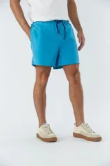 Short de baño celeste liso, con cintura elástica ajustable con cordón negro, dos bolsillos delanteros y uno trasero.