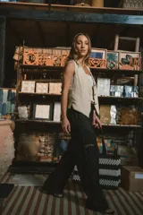 Pantalón de vestir negro de tiro alto, corte recto y pierna ancha. Presenta pliegues frontales y bolsillos laterales.