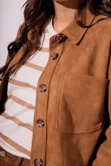 Sobrecamisa negra de gamuza vegana con calce oversize, cuello camisero, cierre con botones a presión, mangas largas con puños abotonados y bolsillos de parche en el pecho.