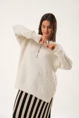 Buzo oversize color beige confeccionado en tejido sintético con destellos de lurex, cuello redondo y manga larga.