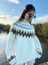 Sweater tejido a mano en lana merino color crema con diseño geométrico en marrón y beige en el cuello, pecho y puños.