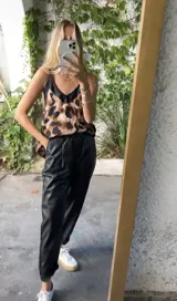 Pantalón babucha verde de cuerina con bolsillos laterales y cinturón fino marrón.