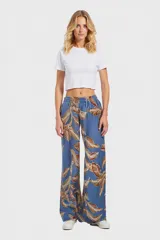 Pantalón ancho de tela estampada con hojas marrones sobre fondo celeste, con cintura elástica.