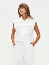 Chaleco corto color blanco, con cuello camisero, sin mangas y con bolsillos frontales.