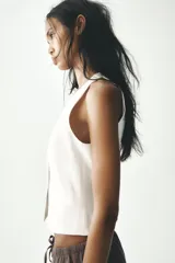 Chaleco blanco con cuello halter y escote en pico. Cierre frontal con botones.