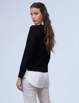 Buzo de hilado fino color beige con cuello y ruedo de gasa blanca que simula una camisa debajo. Presenta escote en V y mangas largas.