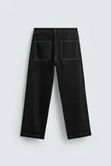 Pantalón relaxed fit de denim negro con costuras blancas en contraste, bolsillos frontales y traseros de parche, cierre frontal con cremallera y botón.